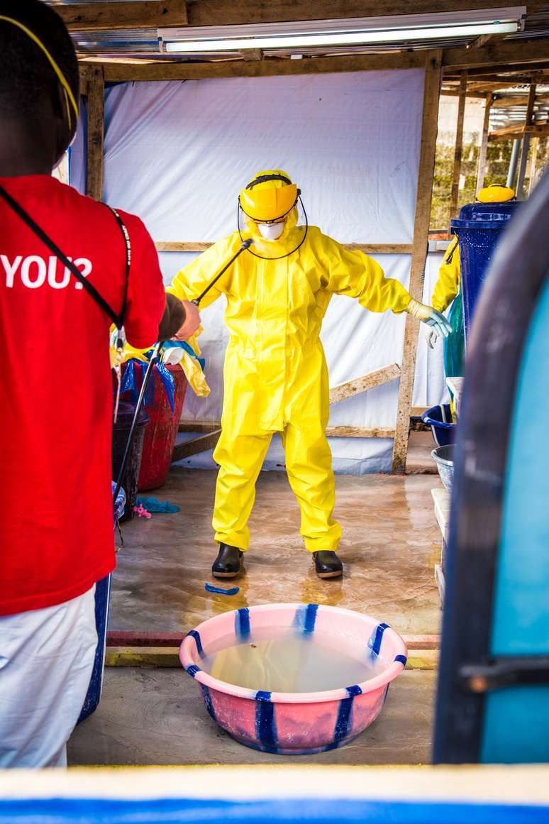 <p>Um agente de saúde vestido com equipamento de proteção é pulverizado com desinfetante após trabalhar em um centro de tratamento de Ebola no oeste de Freetown, Serra Leoa, em 16 de outubro</p>
