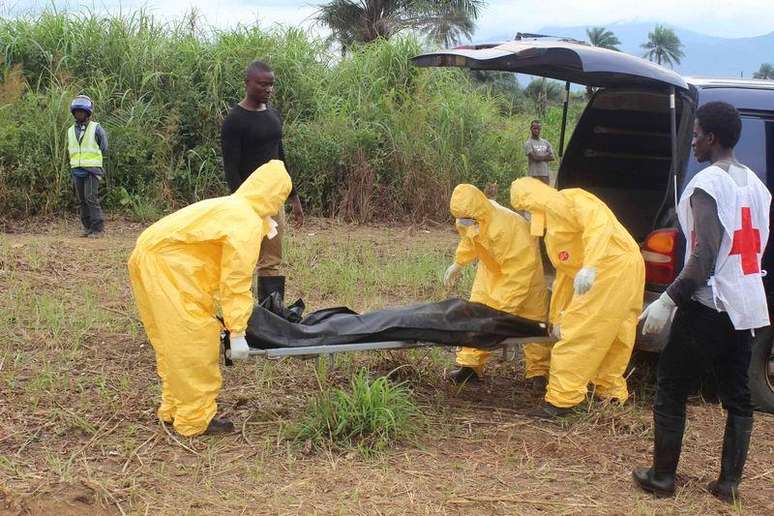<p>Funcionários de serviços de saúde carregam corpo de vítima com ebola no distrito de Waterloo, Freetown (Serra Leoa)</p>