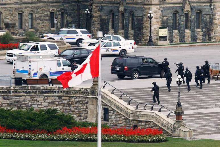 <p>Policiais armados se aproximam do bloco central do Parlamento após um tiroteio, em Ottawa, no Canadá, nesta quarta-feira</p>