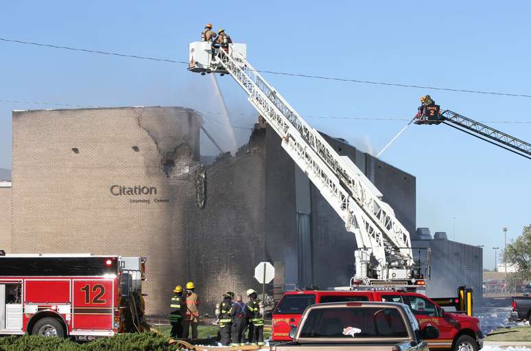 <p>Bombeiros tentam apagar o fogo no prédio do Aeroporto Mid-Continent de Wichita, no Estado norte-americano do Kansas, atingido por um bimotor nesta quinta-feira</p>