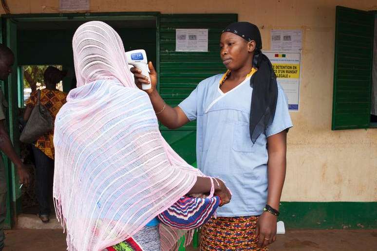 <p>Profissional de saúde verifica temperatura em mulher que deixou Guiné, na fronteira com Mali , em Kouremale</p>