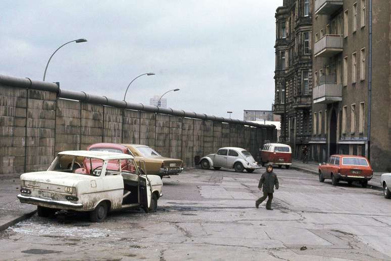 <p>Ve&iacute;culos antigos e uma crian&ccedil;a na frente do Muro de Berlim, em Bethaniendamm, em 8 de Mar&ccedil;o de 1973</p>