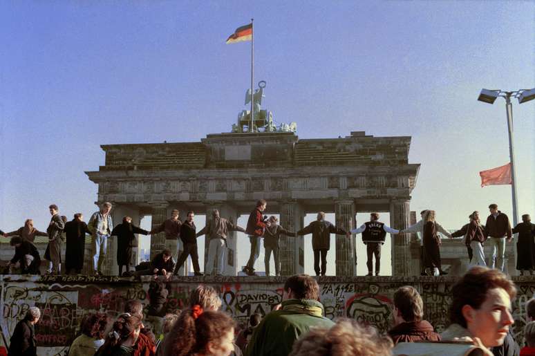 <p>Berlinenses cantam&nbsp;e dan&ccedil;am&nbsp;em cima do Muro de Berlim, para comemorar a abertura das fronteiras em&nbsp;10 de novembro de 1989</p>