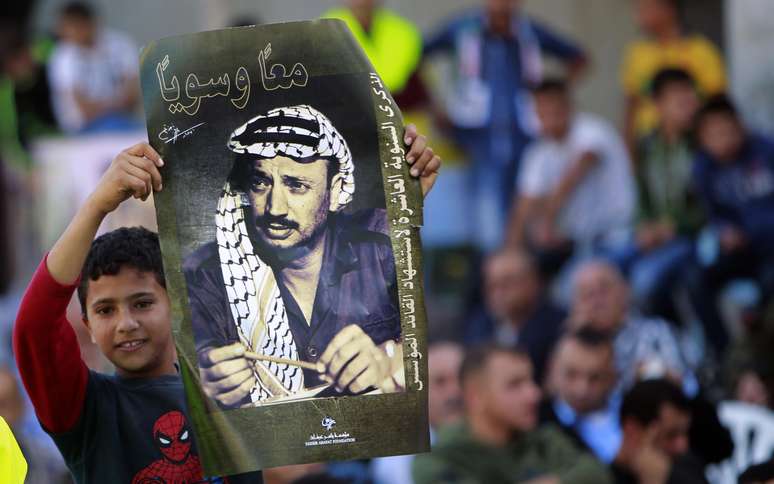 <p>Uma criança palestina segura uma foto do falecido líder Yasser Arafat, durante uma cerimônia que marcou o 10º aniversário da sua morte, na aldeia da Cisjordânia de Al-Yamoun</p>