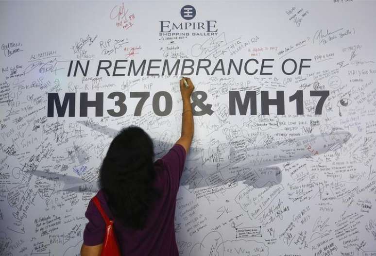 Mulher escreve em painel de mensagem em homenagem a vítimas de voos da Malaysia Arilines MH370 e MH17, em Subang Jaya. 23/07/2014