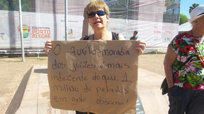 Eliane Lima carrega cartaz que relaciona obscenidade com benefícios do judiciário