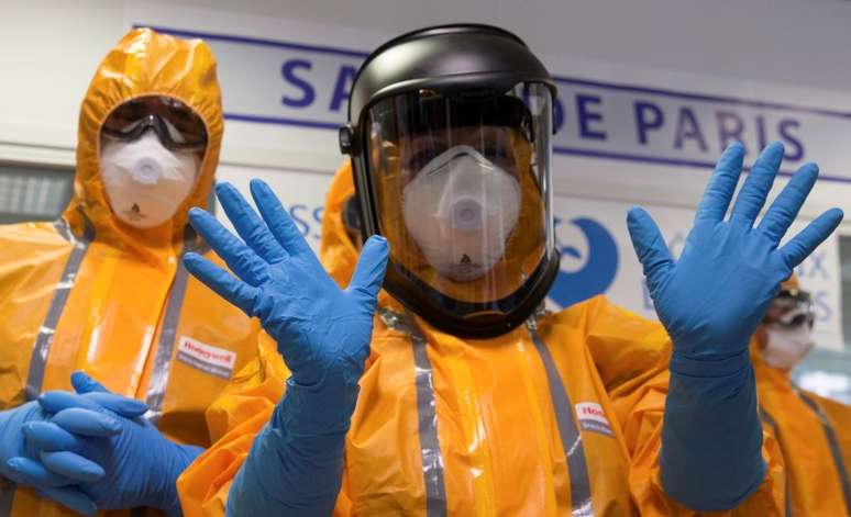 <p>Funcionário do hospital francês, Necker, mostra luvas e roupas de proteção usadas para tratamento de paciente</p>