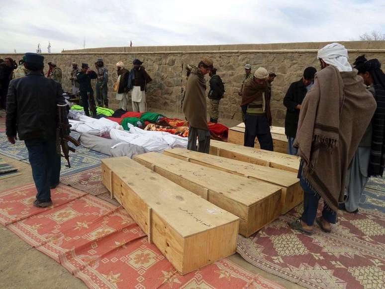 Afegãos reunidos em volta dos corpos das vítimas do ataque suicida no jogo de vôlei. 24/11/2014