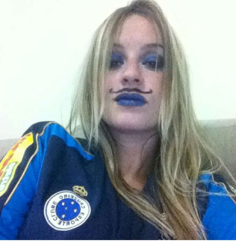 <p>Caracterizada com "bigode" e as cores do clube, Kenia Soares, de Campo Belo (MG), assistiu à vitória do Cruzeiro em casa, com os amigos</p>