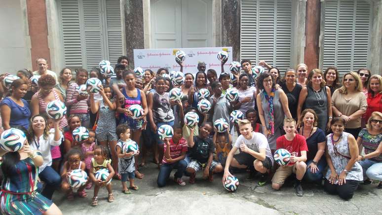 Garotas e garotas da ONG Saúde Criança posam para foto após ganhar bolas doadas por um patrocinador, diante da iniciativa de Ethan