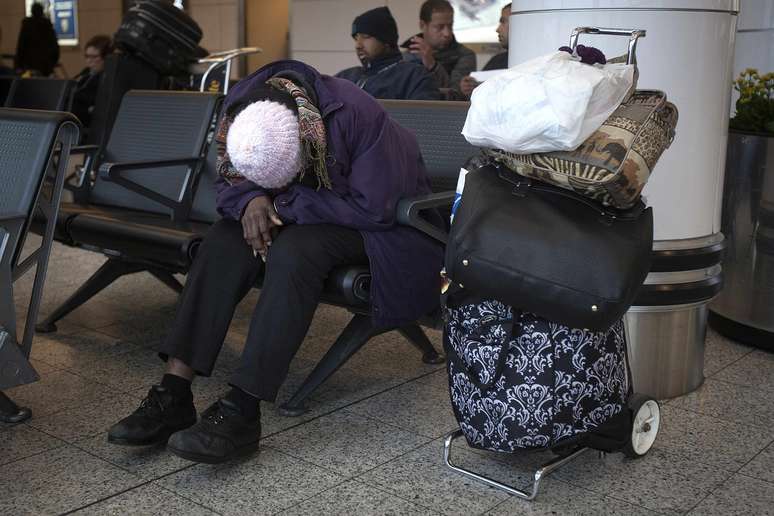 <p>Uma mulher dorme no aeroporto de LaGuardia, em Nova York, na v&eacute;spera do dia de A&ccedil;&atilde;o de Gra&ccedil;as; milhares de voos foram cancelados por causa do mau tempo</p>