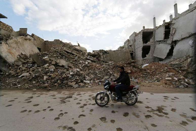 Homem conduz sua motocicleta em frente a escombros de prédios em Maaret al-Naaman, na província de Idlib, Síria. 27/11/2014.