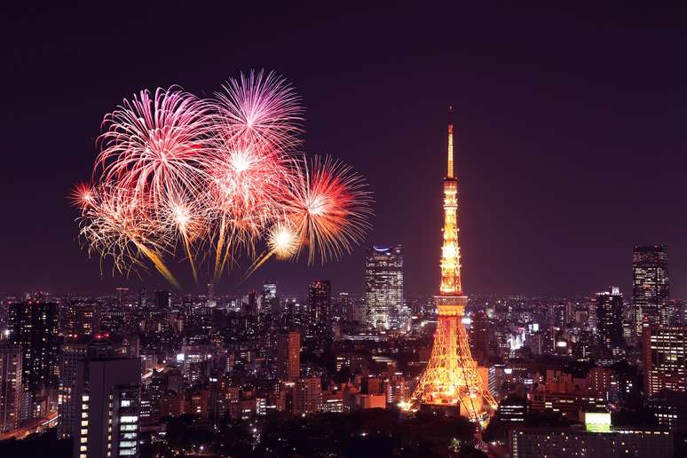 Tokyo Tower (não, não é a Torre Eiffel) ao lado de tímidos fogos; programa de TV e visitas a templos são hábitos japoneses mais comuns no final de ano