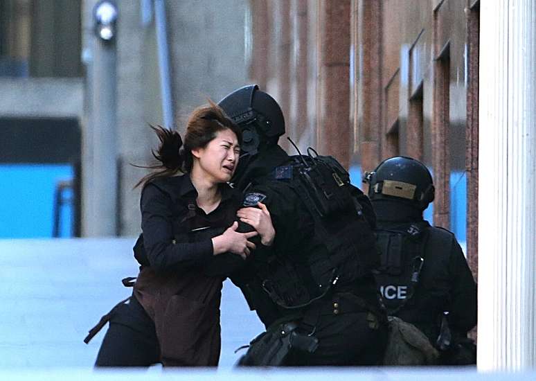 Una mujer corre hacia la policía tras ponerse a salva del hombre armado en la cafetería de Sídney, este lunes 15 de diciembre del 2014.