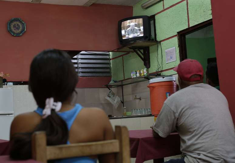 Cubanos acompanham pronunciamento do presidente Raul Castro em um restaurante em Havana; Estados Unidos e Cuba planejam restabelecer relações diplomáticas