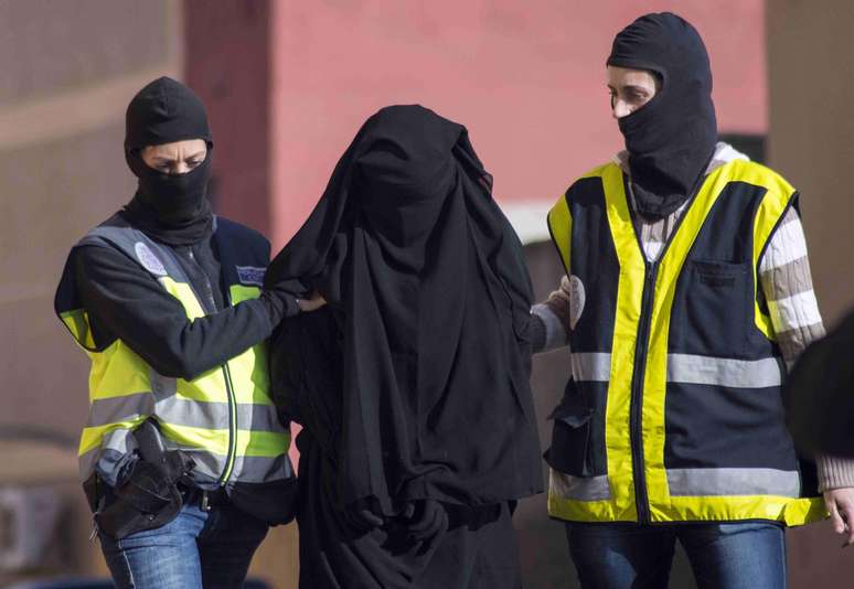 Policiais mascarados espanhóis prendem uma mulher suspeita de participar de uma organização que recrutava mulheres para os jihadistas do Estado Islâmico