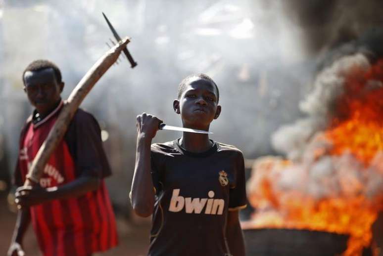 <p>Garoto exibe faca em frente a uma barricada em chamas durante protesto, depois que tropas francesas abriram fogo contra manifestantes que bloqueavam uma estrada em Bambari, na República Centro-Africana, em maio</p><p> </p>