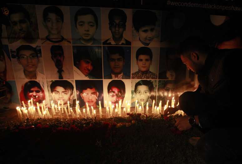 <p>Um homem coloca uma rosa na&nbsp;frente de retratos das v&iacute;timas do ataque talib&atilde; na Escola P&uacute;blica do Ex&eacute;rcito em Peshawar, durante uma vig&iacute;lia &agrave; luz de velas, em Lahore&nbsp;</p>