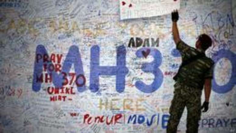 Soldado em frente a mural em homenagem a v&iacute;timas do MH370 (foto: AP)