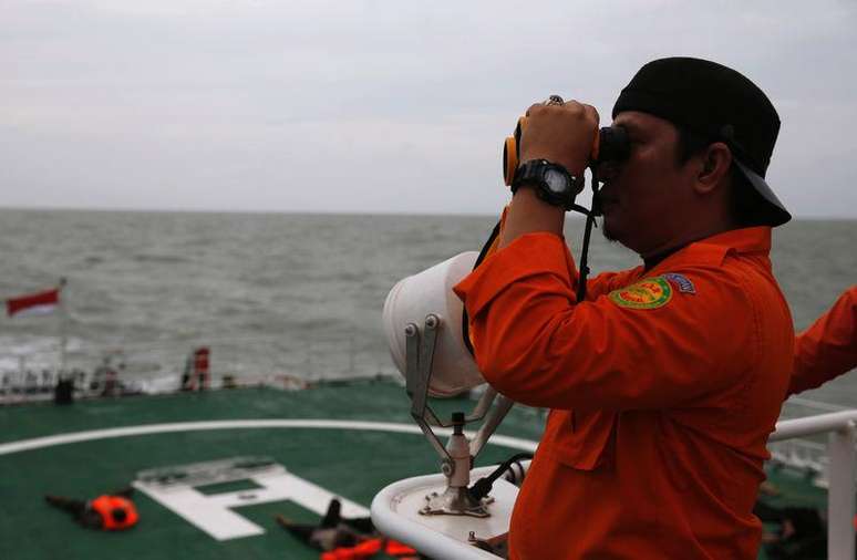 <p>Agente da equipe de resgate da Indonésia usa binóculo para tentar encontrar objetos suspeitos no mar de Java, na Indonésia</p>