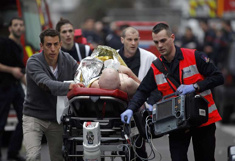Uma pessoa ferida é socorrida após ataque ao escritório da revista satírica Charlie Hebdo, em Paris, em 7 de janeiro