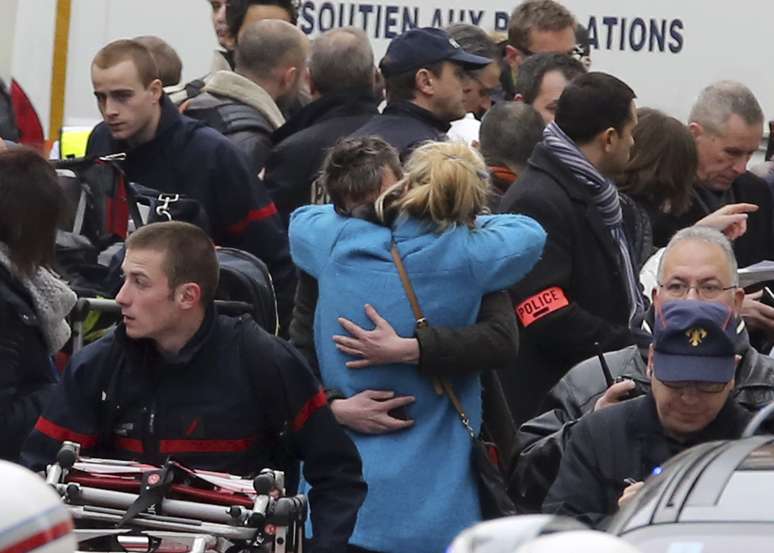 Pessoas se abraçam em frente ao escritório da revista "Charlie Hebdo" após atentado
