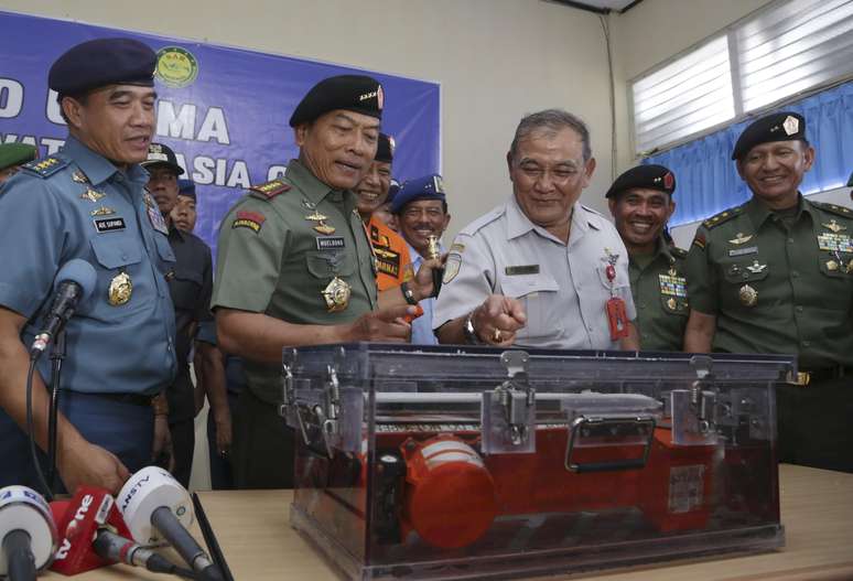 Autoridades da Indonésia olham para uma das caixas-pretas do avião da AirAsia, que caiu no mar de Java, durante uma conferência de imprensa no aeroporto em Pangkalan Bun, Indonésia, em 12 de janeiro