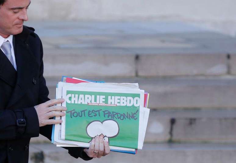 Primeiro-ministro francês Manuel Valls segura uma cópia do semanário Charlie Hebdo ao deixar encontro do gabinete em Paris.  14/01/ 2015.