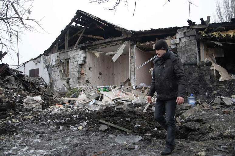 Homem caminha perto de uma residência que, segundo locais, foi recentemente danificada por bombardeios em Donetsk, no leste da Ucrânia, na segunda-feira. 19/01/2015