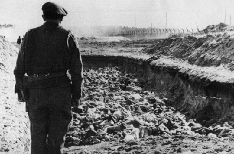 <p>Soldado observa o mar de corpos. Crematório funcionava 24 horas por dia. 90% dos que ali morreram eram judeus sendo alguns prisioneiros, eslavos e descumpridores do regime de Adolf Hitler</p>