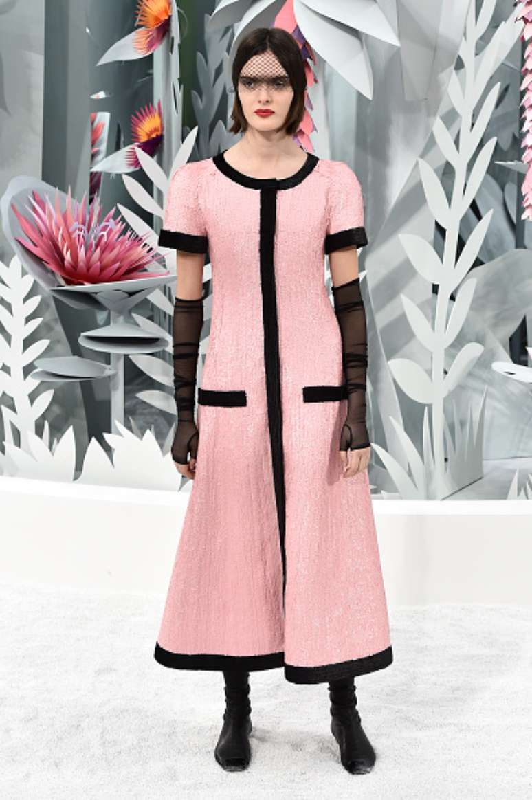 O tradicional casaquinho do tailleur Chanel se alonga e vira um vestido casaco rosa com debrum preto