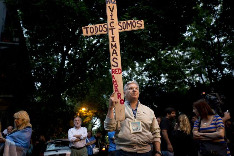<p>Um homem carrega um cruz com a frase: "Somos todos vítimas" em referência à misteriosa morte do promotor Alberto Nisman</p>
