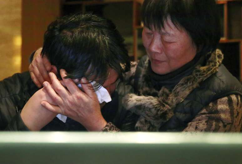 Parentes de uma vítima do voo MH370 choram ao saber, pela televisão, que o desaparecimento da aeronave da Malaysia Airlines foi considerado, oficialmente, um acidente 