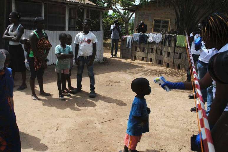 <p>Funcionária de serviço de saúde mede temperatura de menino que teve contato com Ebola em Paynesville, bairro de Monróvia</p>