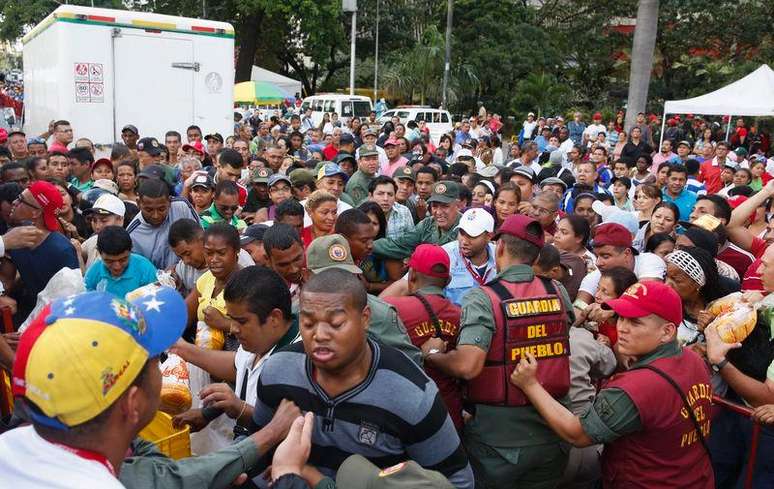 Soldados venezolanos tratan de controlar a la multitud que se aglomeró para intentar comprar pollo en un Mega-Mercal, un mercado estatal subsidiado, en Caracas, 24 de enero de 2015.  Los dueños de una importante cadena de tiendas de Venezuela fueron detenidos por "provocar" una "guerra económica" en el país, anunció el domingo el presidente Nicolás Maduro sin mencionar el nombre del comercio que medios locales identificaron como las farmacias Farmatodo.