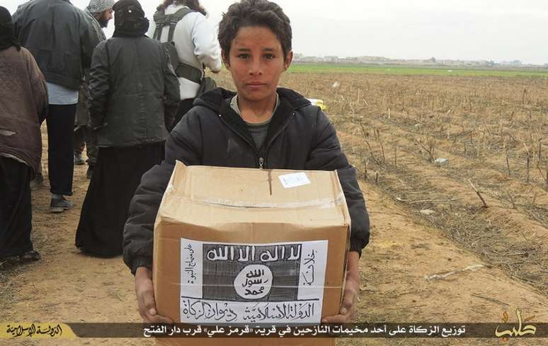 Criança segura um pacote de comida do Programa Mundial de Alimentos da ONU com a logomarca do Estado Islâmico