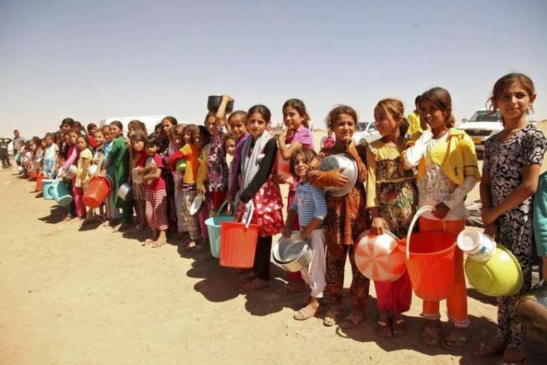 <p>Crianças yazidi, fugidas da violência na cidade iraquiana de Sinjar, fazem fila para receber alimentos num acampamento nos arredores da província de Dohuk</p>