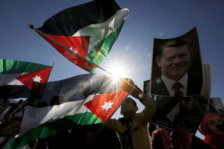 Manifestantes exibem fotos do rei Abdullah, da Jordânia, e do piloto Muath al-Kasaesbeh, além de bandeiras nacionais, durante protesto em apoio ao monarca e contra o Estado Islâmico, em Amã, nesta quinta-feira. 05/02/2015