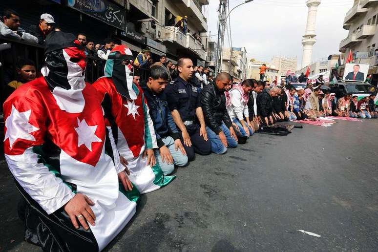 Manifestantes vestidos com a bandeira nacional da Jordânia fazem as orações de sexta-feira antes de uma marcha no centro de Amã, na Jordânia, nesta sexta-feira. 06/02/2015