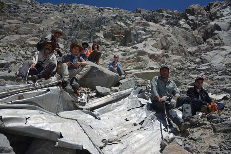 <p>Montanhistas posam para foto com o que seria um destroço do avião desparecido.</p>