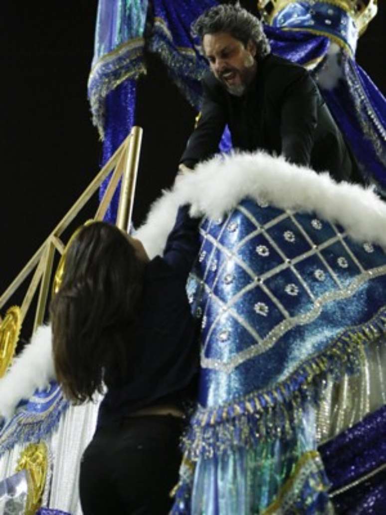 Cora fica pendurada do carro alegórico durante desfile