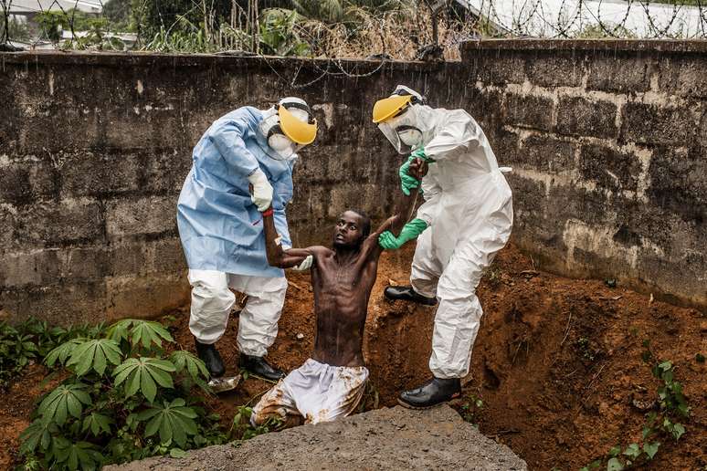 Médicos levam um homem em meio a um delírio induzido pelo ebola para a ala de isolamento de onde tinha escapado