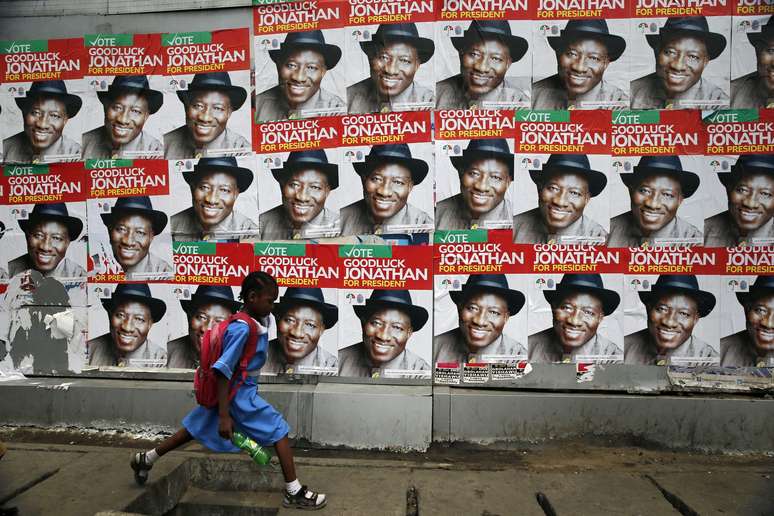 Uma criança corre em frente à propaganda do presidente Goodluck Jonathan para as eleições, que tiveram de ser adiadas devido à violência