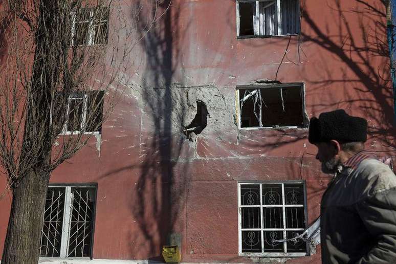 Homem passa por edifício danificado por combates na cidade de Vuhlehirsk, perto de Debaltseve. 18/02/2015