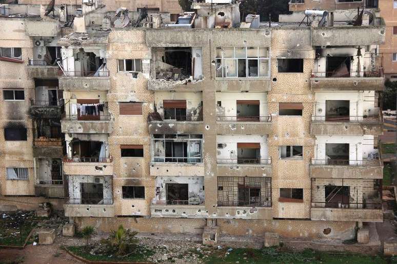 <p>Vista de um prédio danificado por disparos numa área controlada por rebeldes em Homs, na Síria</p>