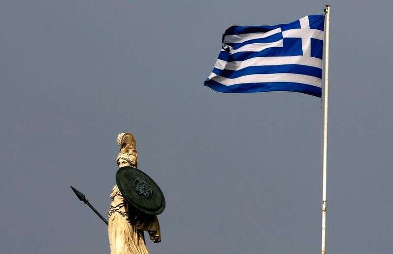 <p>Bandeira da Grécia tremula perto de estátua da deusa Atena, no centro de Atenas</p>