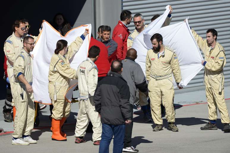 Equipe da McLaren cobre Alonso enquanto o piloto é levado a helicóptero