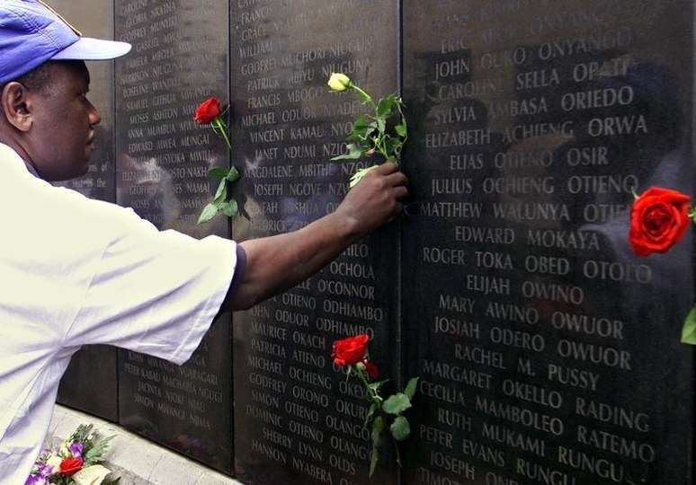 Um homem deposita uma rosa perto do nome de seu familiar no memorial às vítimas dos ataques de 1998 contra a embaixada dos Estados Unidos em Nairóbi, no Quênia. 07/08/2002