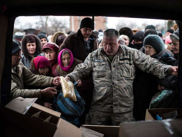 <p>Um voluntário distribui ajuda humanitária aos moradores de Popasna, leste da Ucrânia: cessar-fogo e retirada das armas dá uma esperança para a paz na região</p>