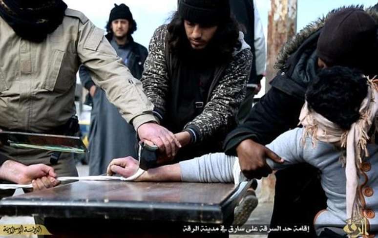 Membros do Estado Islâmico são vistos cortando a mão de um jovem em praça na Síria